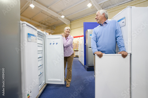 Photo: Mature couple shopping for appliances, smiling at each other, low angle view Mature couple shopping for appliances, smiling at each other, low angle view