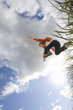 Girl (7-9 years) jumping from grass outdoors, low angle view