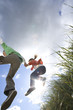 Father and daughter (7-9 years) jumping from grass outdoors, low angle view