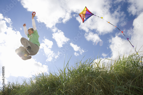 Photo: Boy (7-9 years) flying kite outdoors, low angle view Boy (7-9 years) flying kite outdoors, low angle view