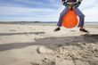 Girl (8-10) playing on inflatable hopper on beach, low section