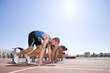 Male sprinters on starting blocks, low angle view (sun flare)