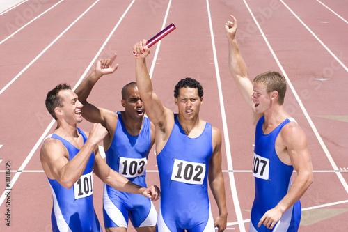 Photo: Group of male athletes with arms raised in celebration, elevated view Group of male athletes with arms raised in celebration, elevated view