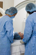 Photo: Doctors in scrubs and surgical masks scanning patient lying on hospital operating table Doctors in scrubs and surgical masks scanning patient lying on hospital operating table