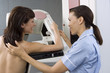 Patient having breast scan in hospital, nurse assisting, smiling, side view