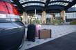 Luggage beside parked car outside hotel