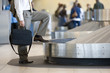 Photo: Businessman waiting for luggage in airport baggage claim area, side view, low section Businessman waiting for luggage in airport baggage claim area, side view, low section