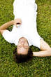Man lying on the grass listening to personal stereo