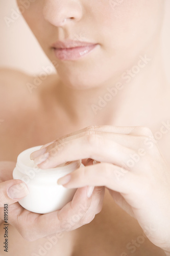 Photo: Young woman with pot of moisturising cream Young woman with pot of moisturising cream