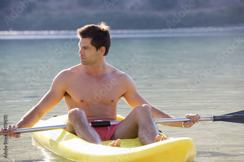 Photo: A man canoeing on a lake A man canoeing on a lake