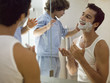 Boy applying shaving foam on his father.