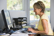 Woman in home office using computer smiling