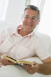 Man in living room reading book smiling Man in living room reading book smiling