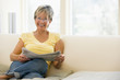 Woman in living room reading newspaper smiling