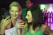 Photo: Close-up of two young women standing at a bar counter and holding martini glasses Close-up of two young women standing at a bar counter and holding martini glasses