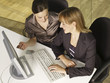 High angle view of two businesswomen working on a desktop PC