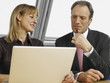 Businessman and a businesswoman sitting in front of a laptop and discussing