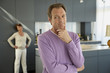 Man standing with his hand on his chin and a woman standing behind him