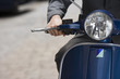 Photo: Man riding on scooter in street, mid-section, front view, close-up, focus on headlight Man riding on scooter in street, mid-section, front view, close-up, focus on headlight