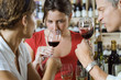 Friends wine tasting in off-licence, woman smelling glass of red wine (differential focus)