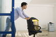 Photo: Businessman in jeans using office chair to move boxes in empty office, smiling, profile Businessman in jeans using office chair to move boxes in empty office, smiling, profile