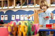 Photo: Multi-coloured scissors in classroom, focus on boy (4-6) playing with weight scale in background Multi-coloured scissors in classroom, focus on boy (4-6) playing with weight scale in background