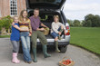 Photo: Family posing beside car boot with basket of vegetables in driveway, smiling, portrait Family posing beside car boot with basket of vegetables in driveway, smiling, portrait