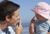 Photo: Father and daughter (2-4) playing on beach, touching noses with fingers, smiling, side view Father and daughter (2-4) playing on beach, touching noses with fingers, smiling, side view