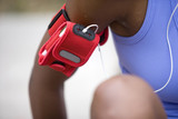 Photo: Female jogger wearing MP3 player strapped to arm in red case, mid-section, close-up, front view (differential focus) Female jogger wearing MP3 player strapped to arm in red case, mid-section, close-up, front view (differential focus)