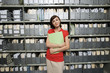 Photo: Woman wearing red top, standing in office archive, carrying file, smiling, front view, portrait Woman wearing red top, standing in office archive, carrying file, smiling, front view, portrait