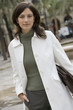 Photo: Businesswoman in polo neck top and white coat standing in plaza, carrying briefcase, portrait (tilt) Businesswoman in polo neck top and white coat standing in plaza, carrying briefcase, portrait (tilt)