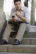 Photo: Businessman sitting on steps, holding personal electronic organiser, briefcase in lap, outdoors Businessman sitting on steps, holding personal electronic organiser, briefcase in lap, outdoors