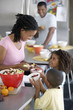 Photo: Two generation family preparing food at home, mother serving fruit salad to children (6-9) Two generation family preparing food at home, mother serving fruit salad to children (6-9)