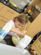 Photo: Girl (6-8) standing in kitchen, mixing flour, eggs and milk in glass bowl with wooden spoon (tilt) Girl (6-8) standing in kitchen, mixing flour, eggs and milk in glass bowl with wooden spoon (tilt)