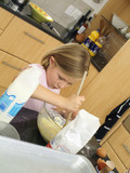 Photo: Girl (6-8) standing in kitchen, mixing flour, eggs and milk in glass bowl with wooden spoon (tilt) Girl (6-8) standing in kitchen, mixing flour, eggs and milk in glass bowl with wooden spoon (tilt)