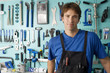 Photo: Man standing in front of display rack in tool shop, smiling, front view, portrait Man standing in front of display rack in tool shop, smiling, front view, portrait