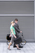 Photo: Businessman walking with businesswoman on pavement, man pushing folding commuter bicycle Businessman walking with businesswoman on pavement, man pushing folding commuter bicycle