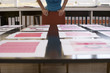 Photo: Woman looking at various designs arranged on large table in office, surface level Woman looking at various designs arranged on large table in office, surface level