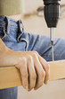 Photo: Woman doing DIY at home, drilling hole in timber with power drill, close-up, mid-section Woman doing DIY at home, drilling hole in timber with power drill, close-up, mid-section