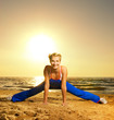 Beautiful young woman doing fitness exercise on a beach