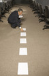 Side view of a businessman crouching and picking up papers