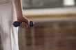Mid section view of a woman holding a dumbbell