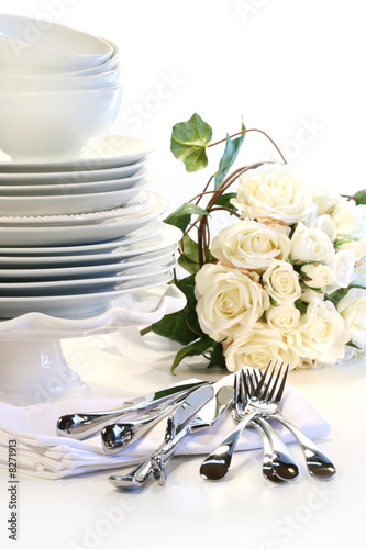 White plates stacked with utencils and roses