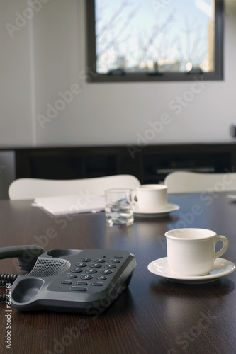Photo: Close-up of a telephone with a tea cup and a saucer on a desk in an office Close-up of a telephone with a tea cup and a saucer on a desk in an office