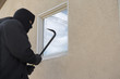 Burglar using crowbar to break into house