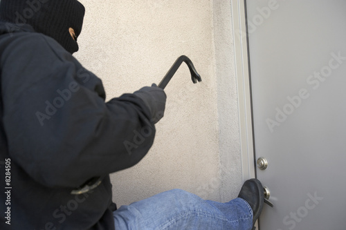 Photo: Burglar kicking door of house Burglar kicking door of house