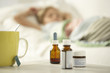 Photo: Close-up of a cup with medicine bottles on a table and a girl sleeping on the bed in the background Close-up of a cup with medicine bottles on a table and a girl sleeping on the bed in the background