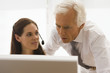 Foto: Businesswoman wearing a headset with a businessman looking at a computer monitor in an office Businesswoman wearing a headset with a businessman looking at a computer monitor in an office