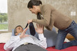 Woman yanking man's tie in bedroom