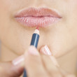 A young woman applying lip liner